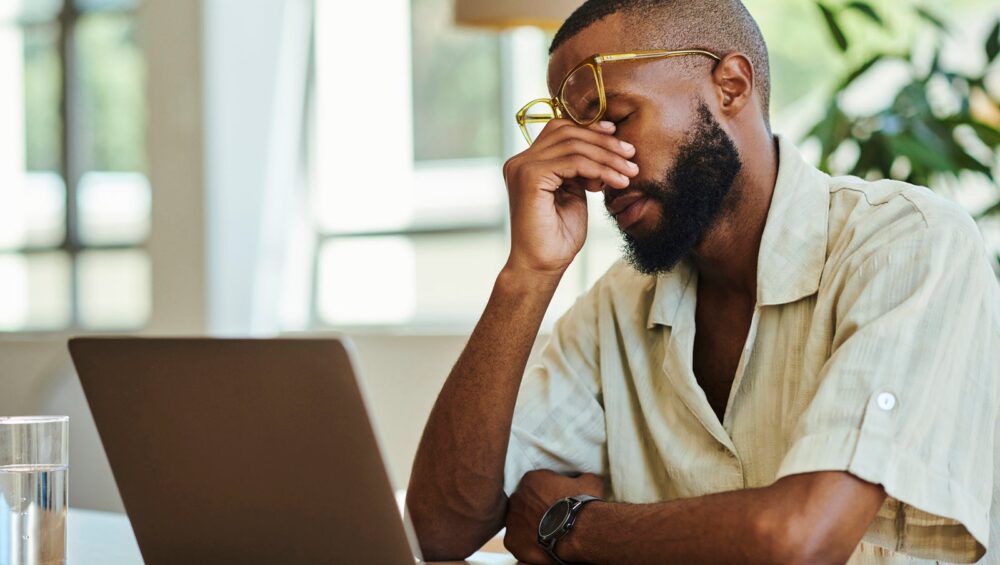 Young African man with laptop working indoors, home office concept. stock photo