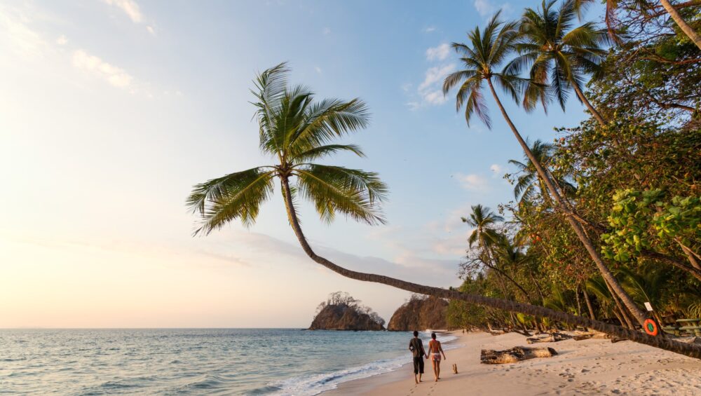 Couple of tourists walking on exotic beach at sunset, Costa Rica
